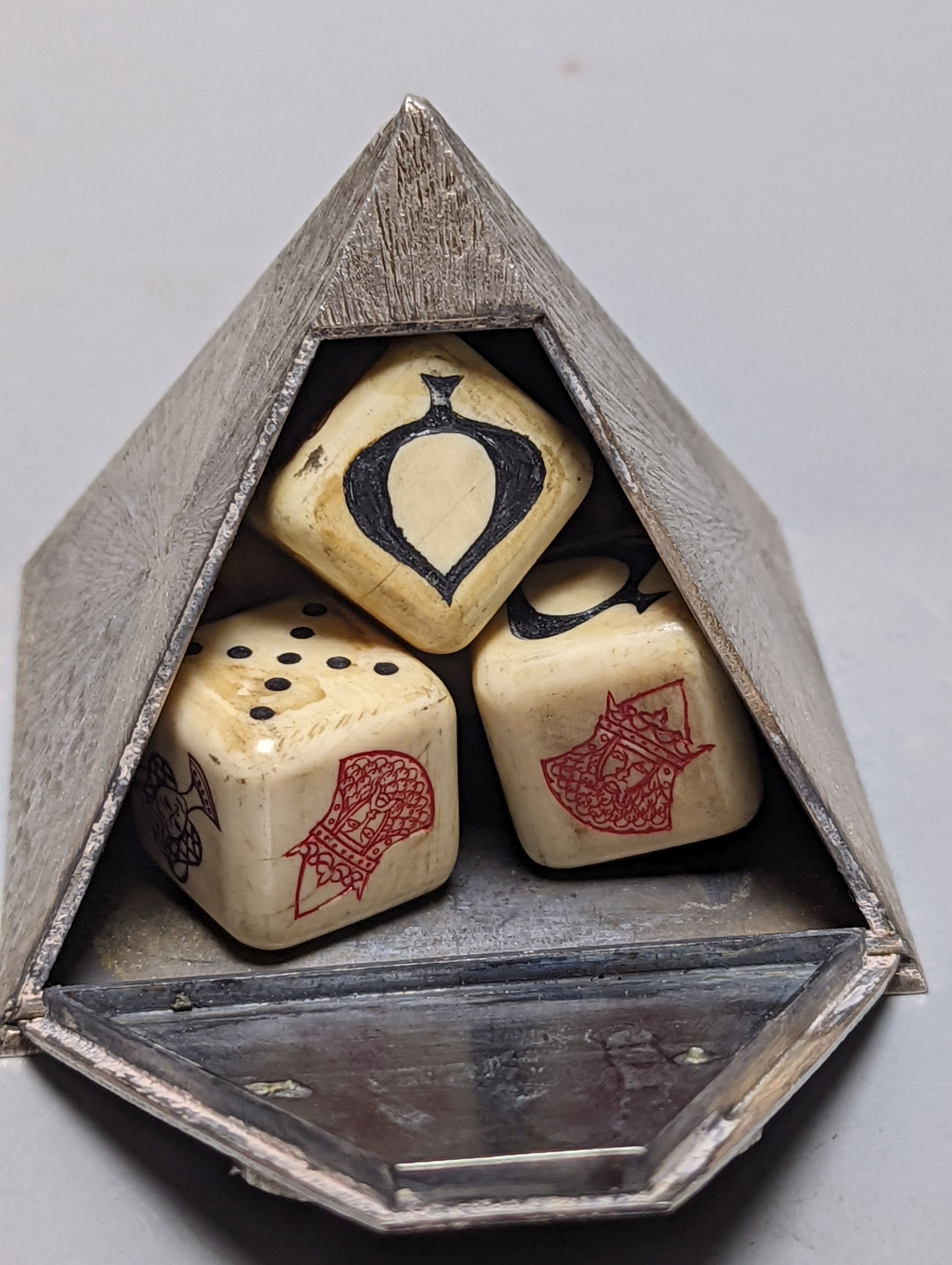 A boxed Collingwood of Conduit Street white metal pyramid shaped box, containing five dice and with applied oval plaque, height 61mm.